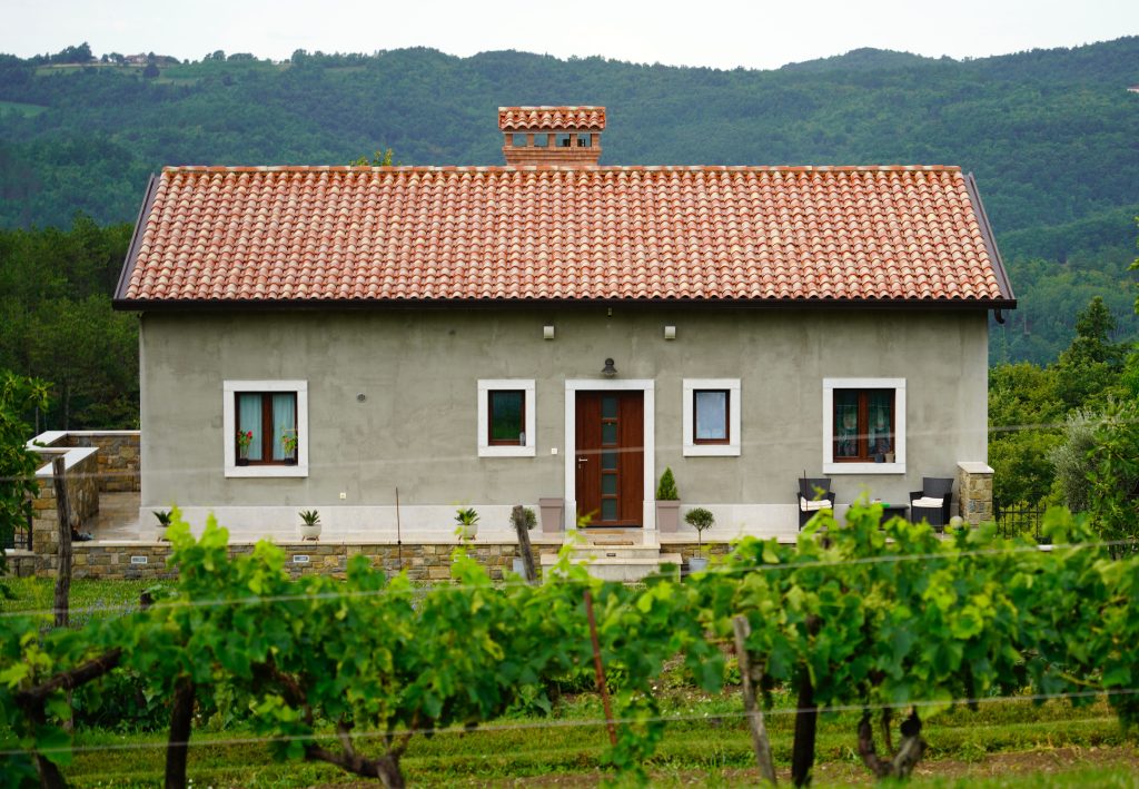 A picturesque house in Hum, Croatia, with lush vineyards and forested hills.