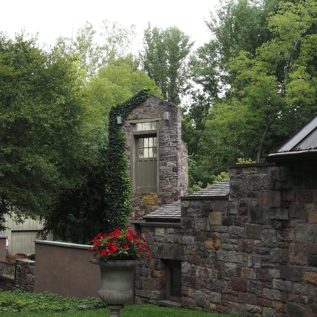 Charming stone wall with ivy and flowers against a lush green backdrop in Pennsylvania.